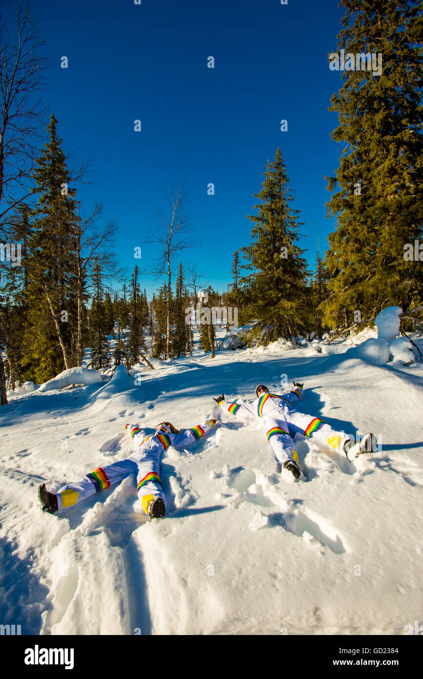 Couple doing snow angels wearing matching Rainbow Ski Suits, Kakslauttanen Igloo West Village, Saariselka, Finland, Scandinavia Stock Photo
