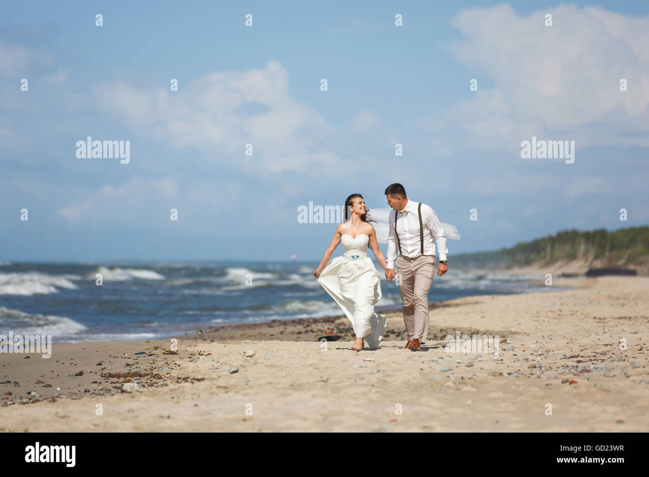 Cheerful wedding couple running on the beach at summer time Stock Photo