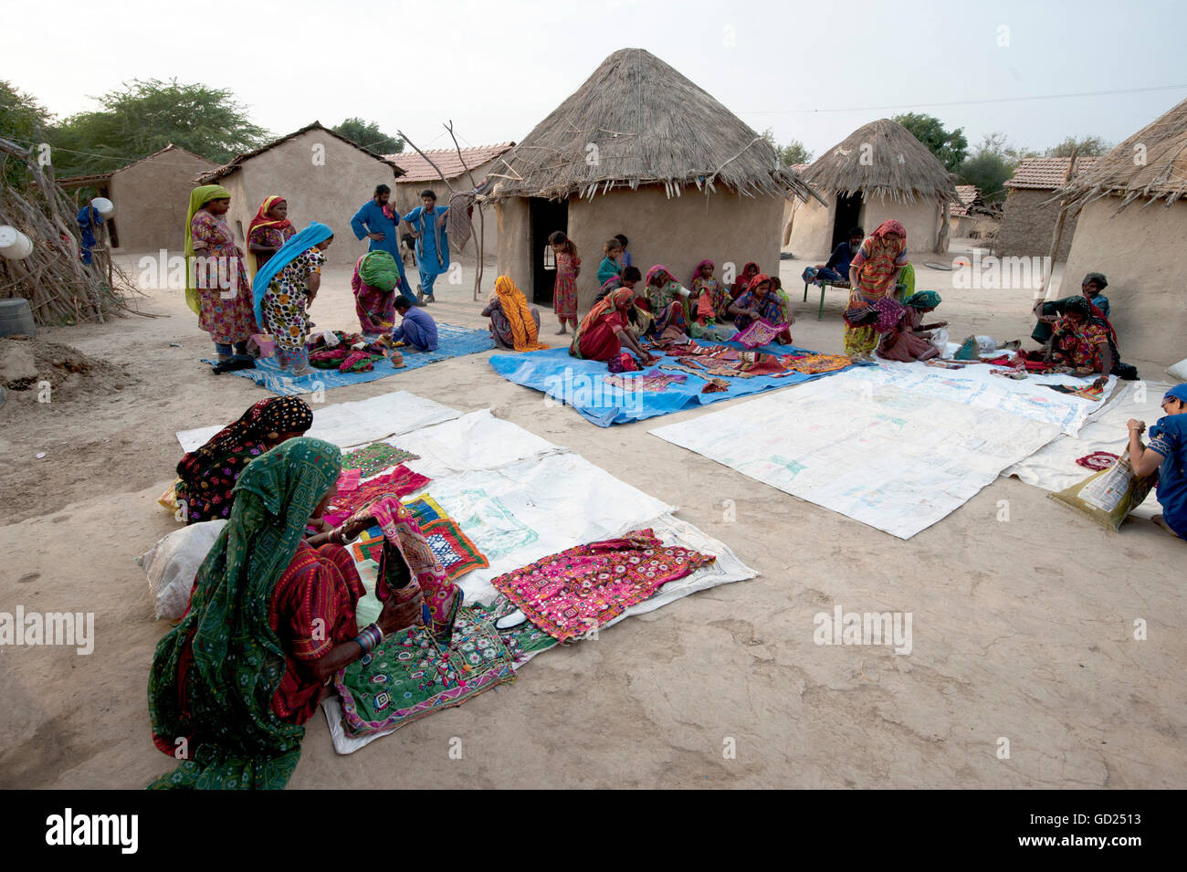 Pathan village women showing traditional embroideries in front of mud & thatched tribal houses, Jarawali, Kutch, Gujarat, India Stock Photo