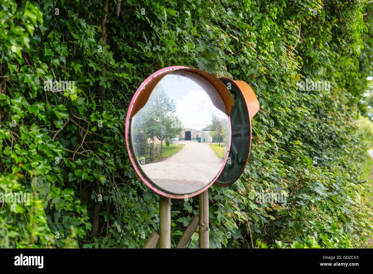 road safety wide angle convex mirror to assist drivers coming out of driveway onto main road through village UK England GB Stock Photo