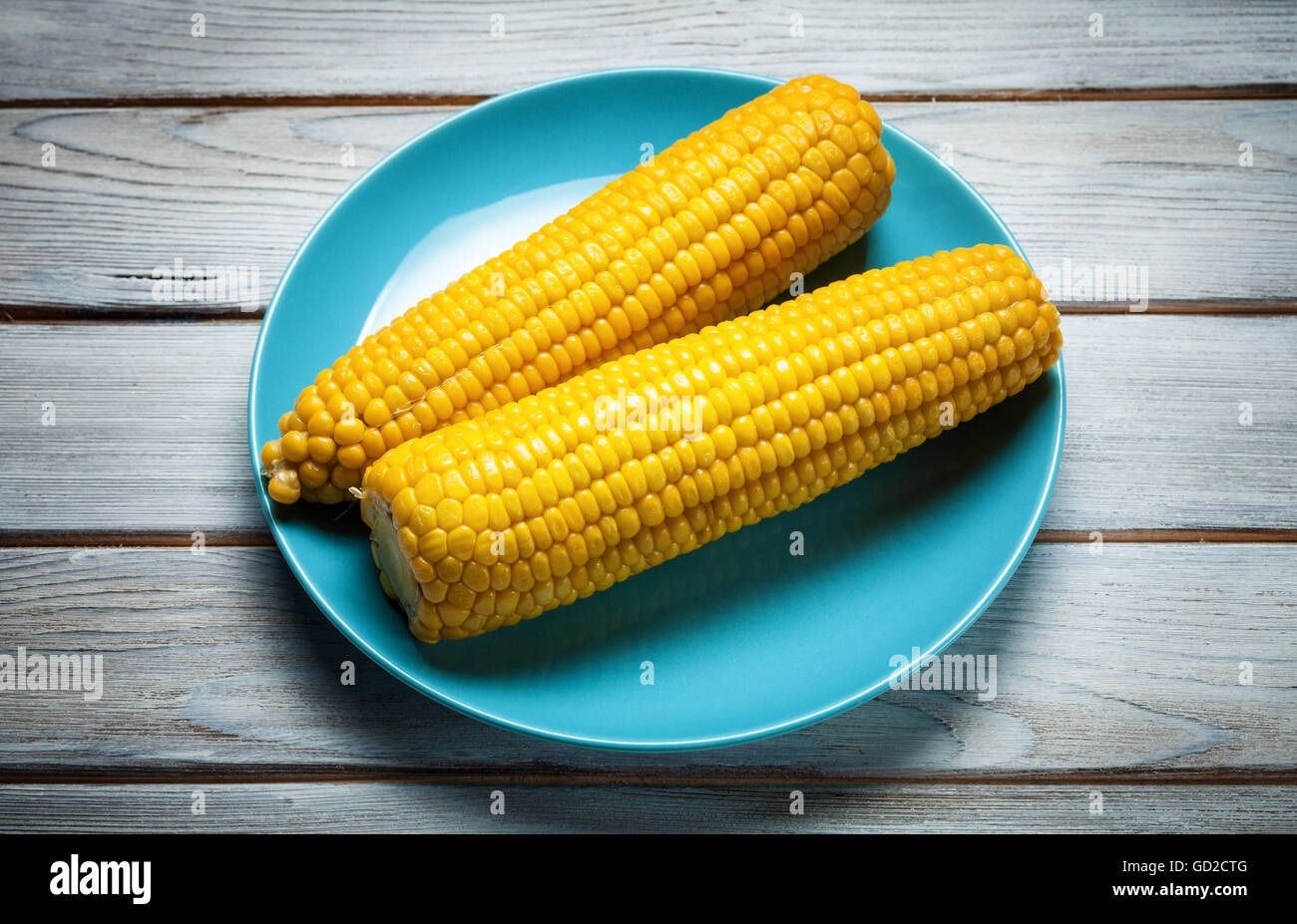 boiled corn on blue plate on white wooden background Stock Photo