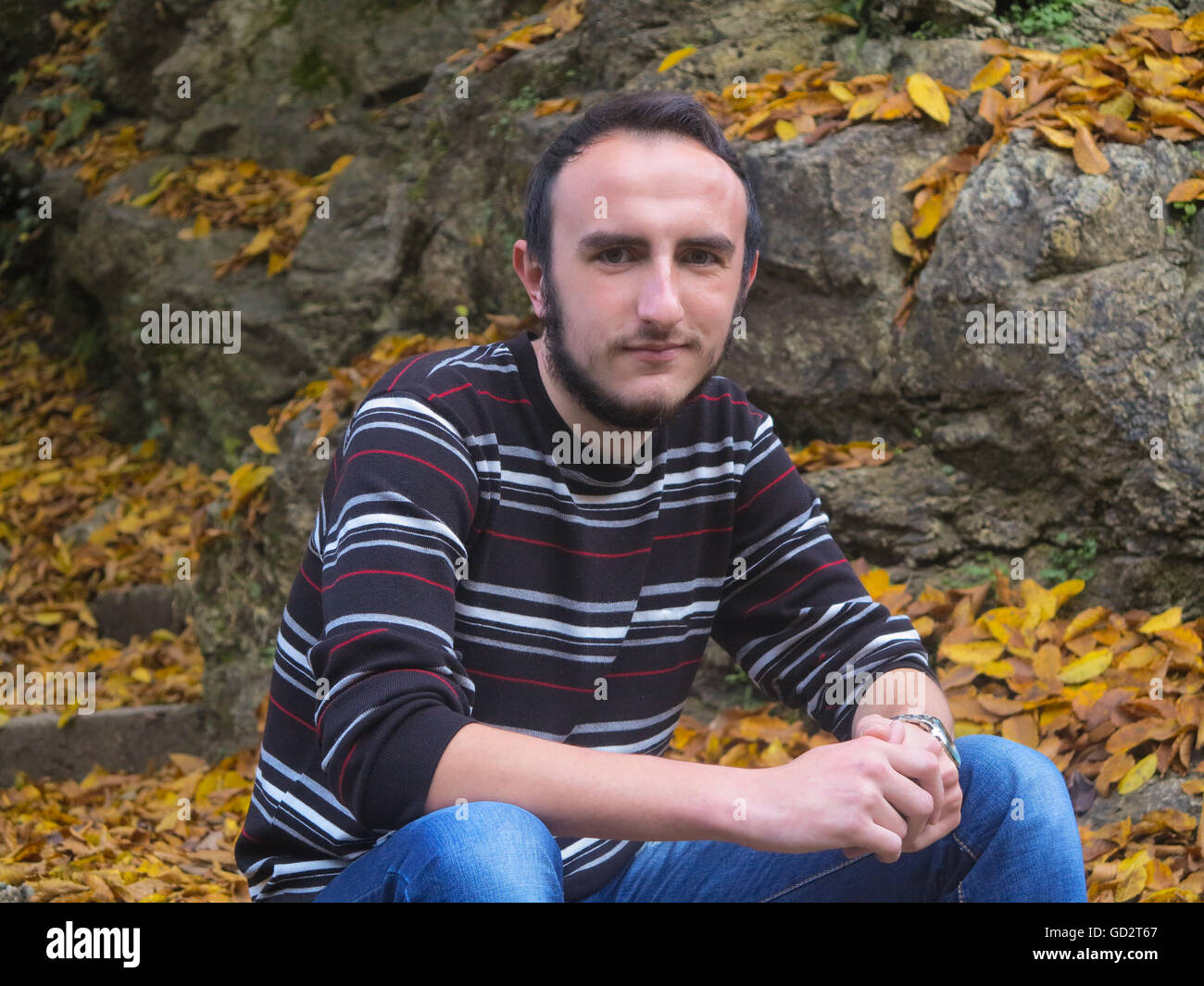 Autumn portrait of young man sitting on the steps Stock Photo - Alamy