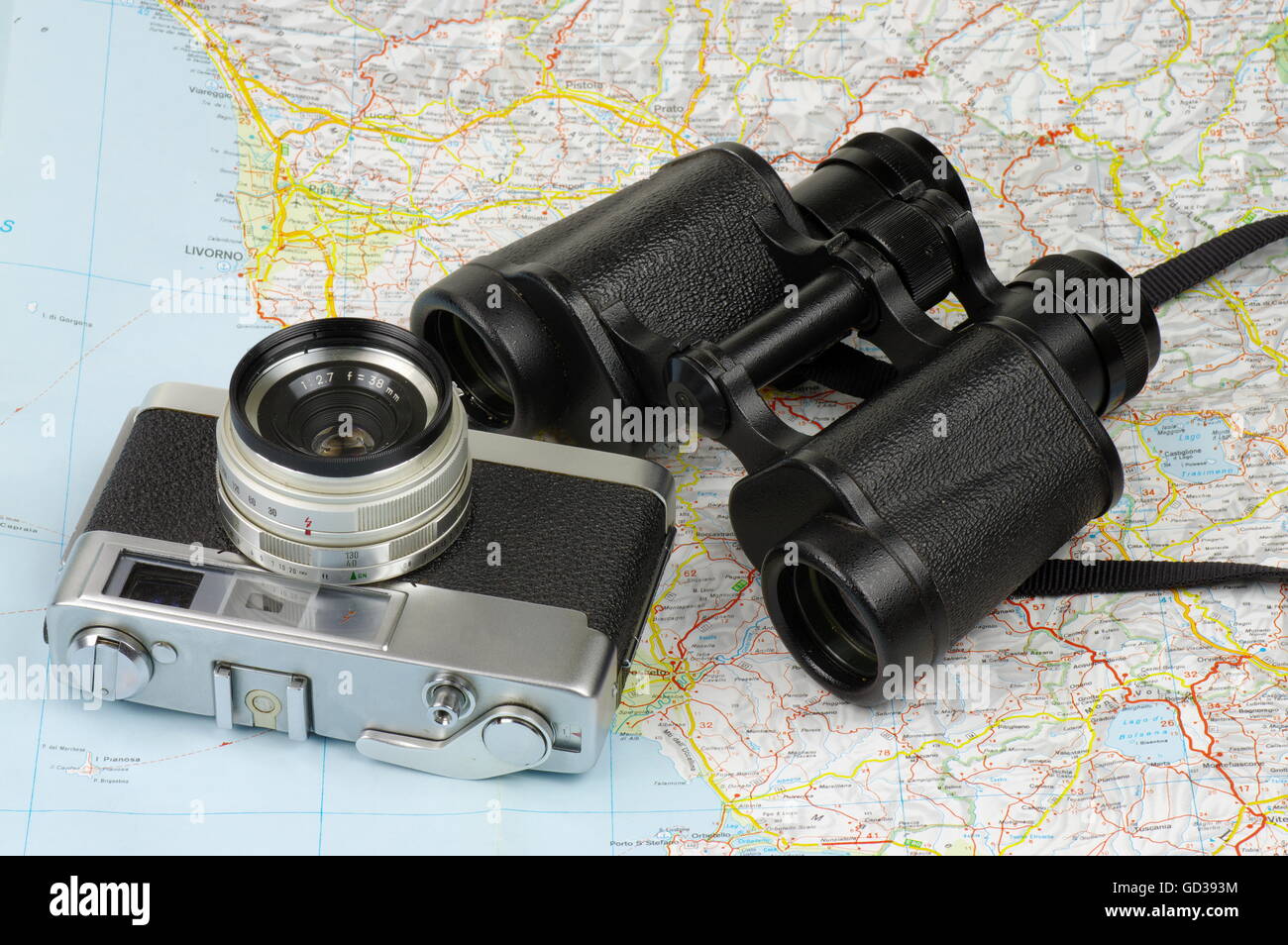Porro binoculars and old rangefinder analog camera lying on the map. Stock Photo