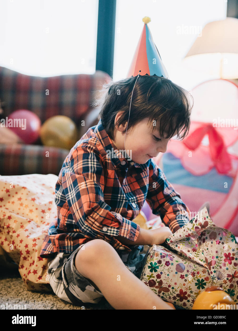 A boy unwrapping his presents at his birthday party. Stock Photo