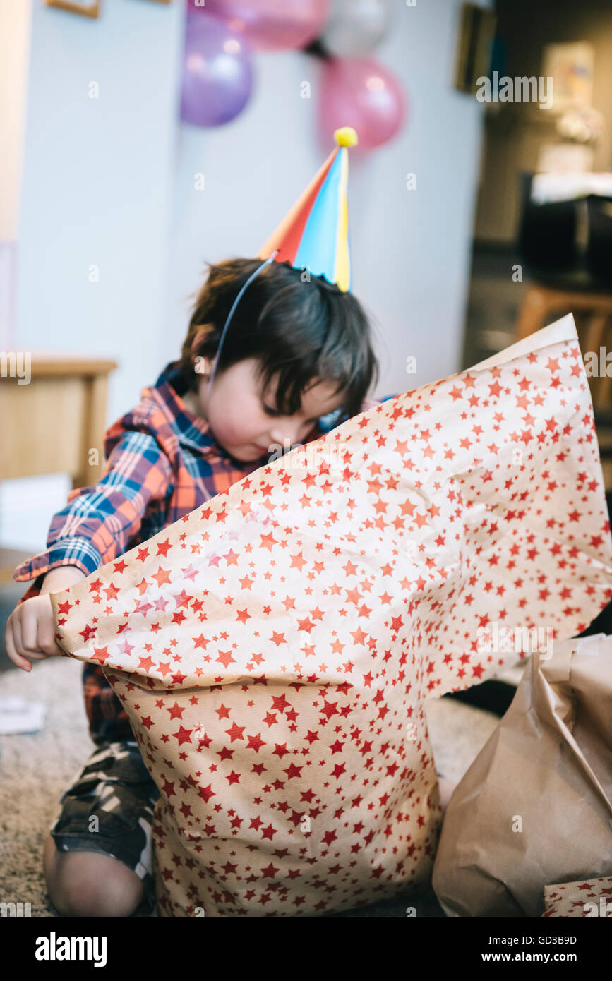 A boy unwrapping presents at a birthday party. Stock Photo