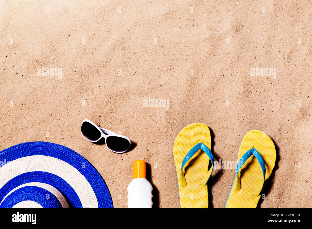 Pair of flip flop sandals, sunglasses, hat and sunscreen. Stock Photo