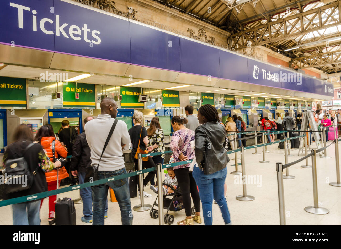 People queue to buy railway tickets at ticket office in Victoria Station, London. Stock Photo