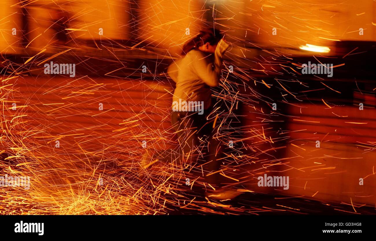 A woman runs through a hail of sparks as a huge bonfire in the Shankill