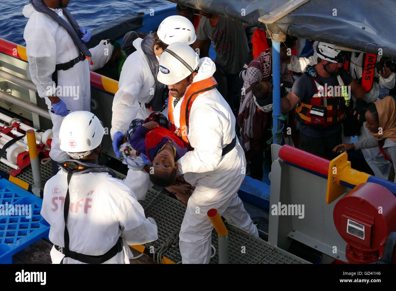 Mediterranean, 17 miles off Libya coast, 12th July, 2016. A humanitarian group recovered the bodies of four migrants and rescued around 400 survivors on Tuesday from an overcrowded wooden boat in the Mediterranean en route to Italy from Libya. The dead suffocated below deck, said the Malta-based Migrant Offshore Aid Station, whose rescue ship carried out the operation. Credit:  Adam Alexander/Alamy Live News Stock Photo