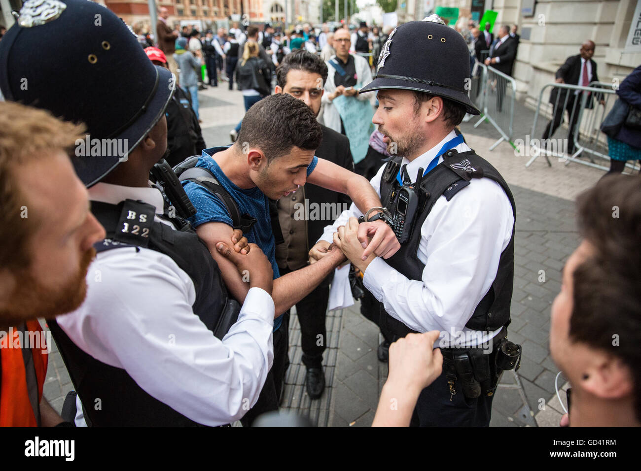 London, UK. 11th July, 2016. Bahraini human rights campaigner Isa Alaali points out that handcuffs have been secured too tightly following arrest during a protest outside an official reception for the Farnborough International arms fair attended by arms dealers at the Science Museum. Some arms dealers attending the reception are believed to have been turned away as a result of the protest organised by the Campaign Against Arms Trade. Protesters were objecting in particular to arms sales to Saudi Arabia, used in human rights abuses against the Yemeni people. Credit:  Mark Kerrison/Alamy Live Ne Stock Photo