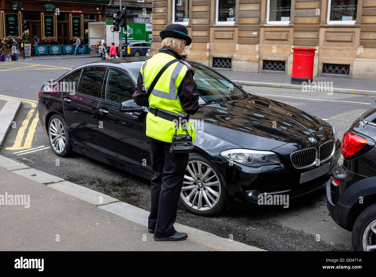 Traffic warden issuing a parking ticket to a BMW saloon car parked illegally, Queen Street, Glasgow, Scotland, UK Stock Photo