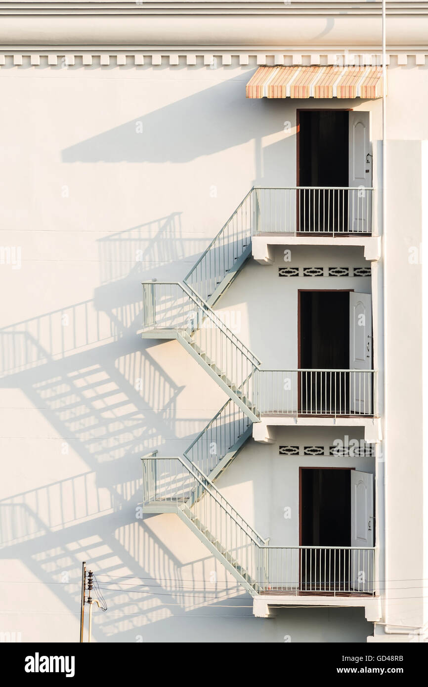 fire escape with afternoon shadows on exterior white wall. Stock Photo