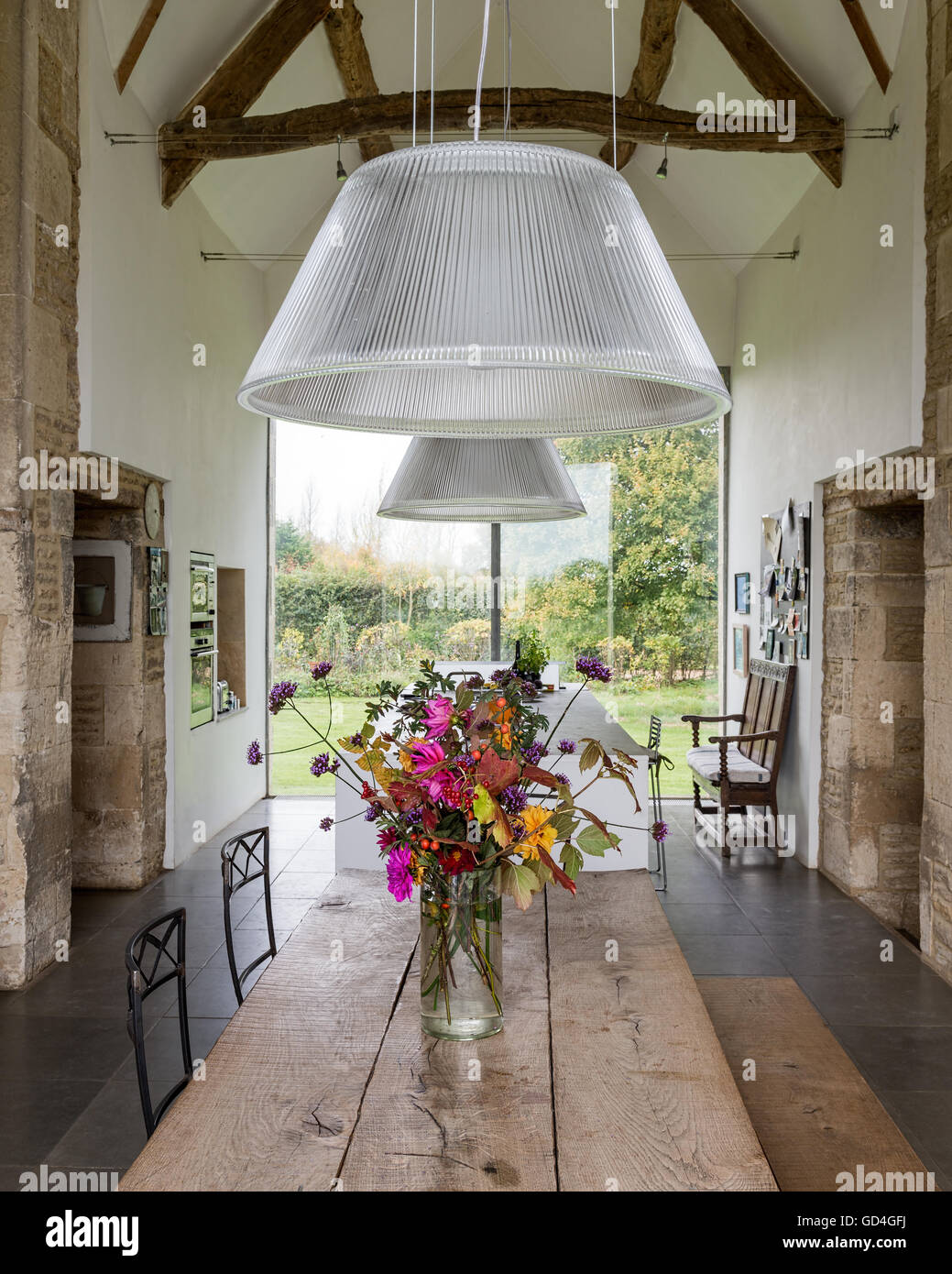 Timber-framed beamed ceiling above refectory style table in double-height barn conversion Stock Photo