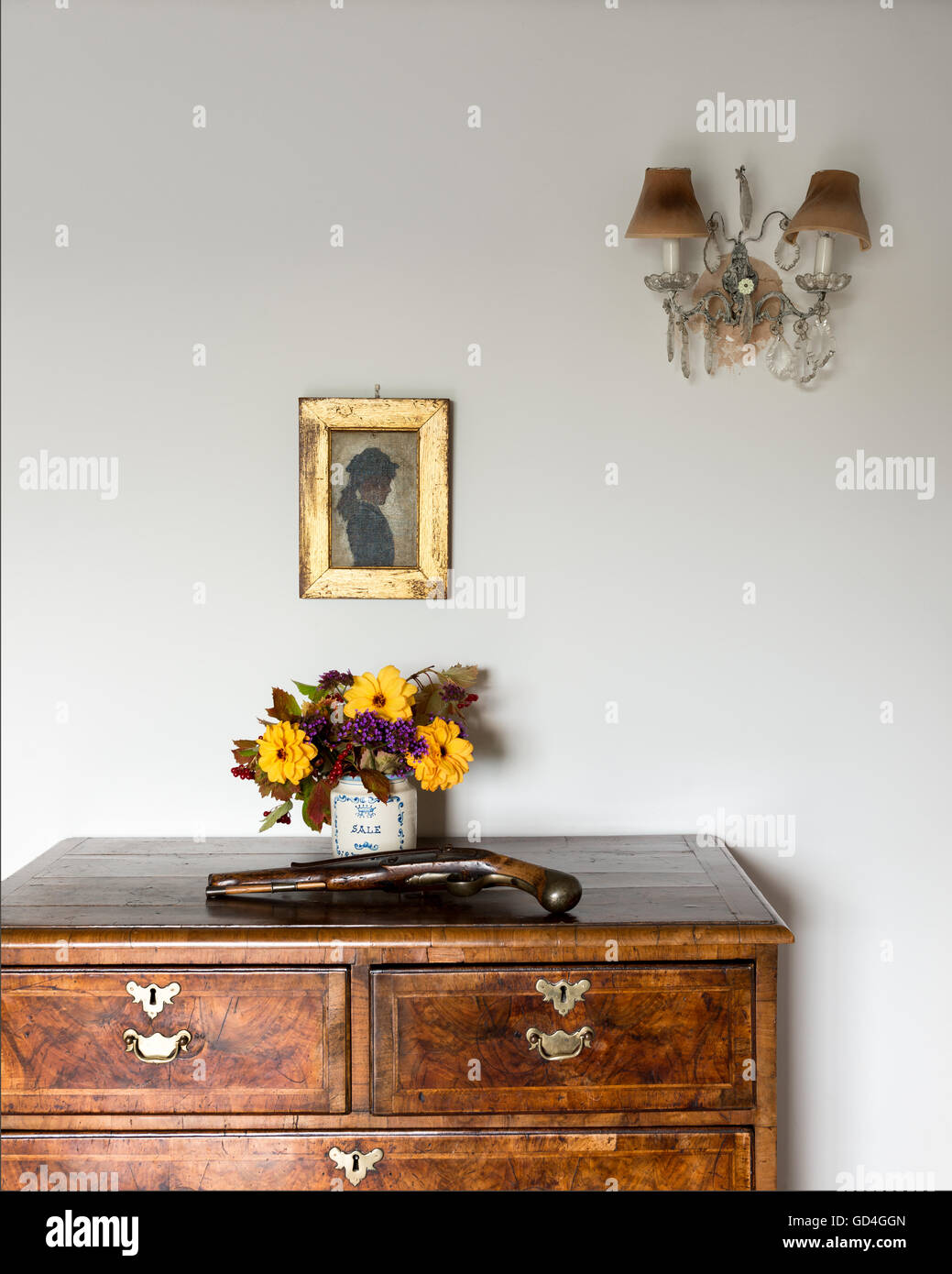 Antique handgun on chest of drawers with gilt framed artwork Stock Photo