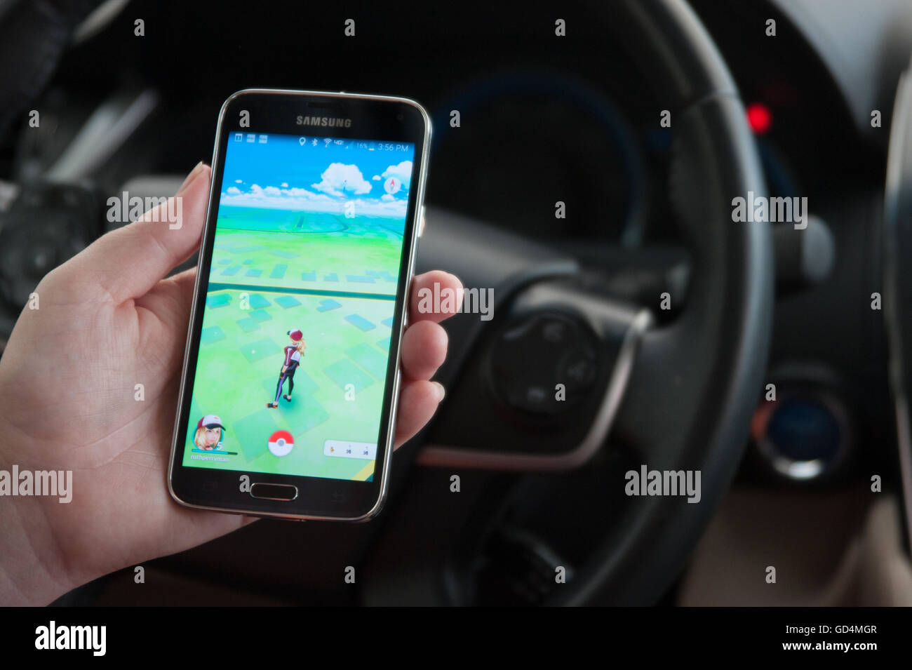 Woman sitting in a car and playing a Pokemon Go game Stock Photo - Alamy