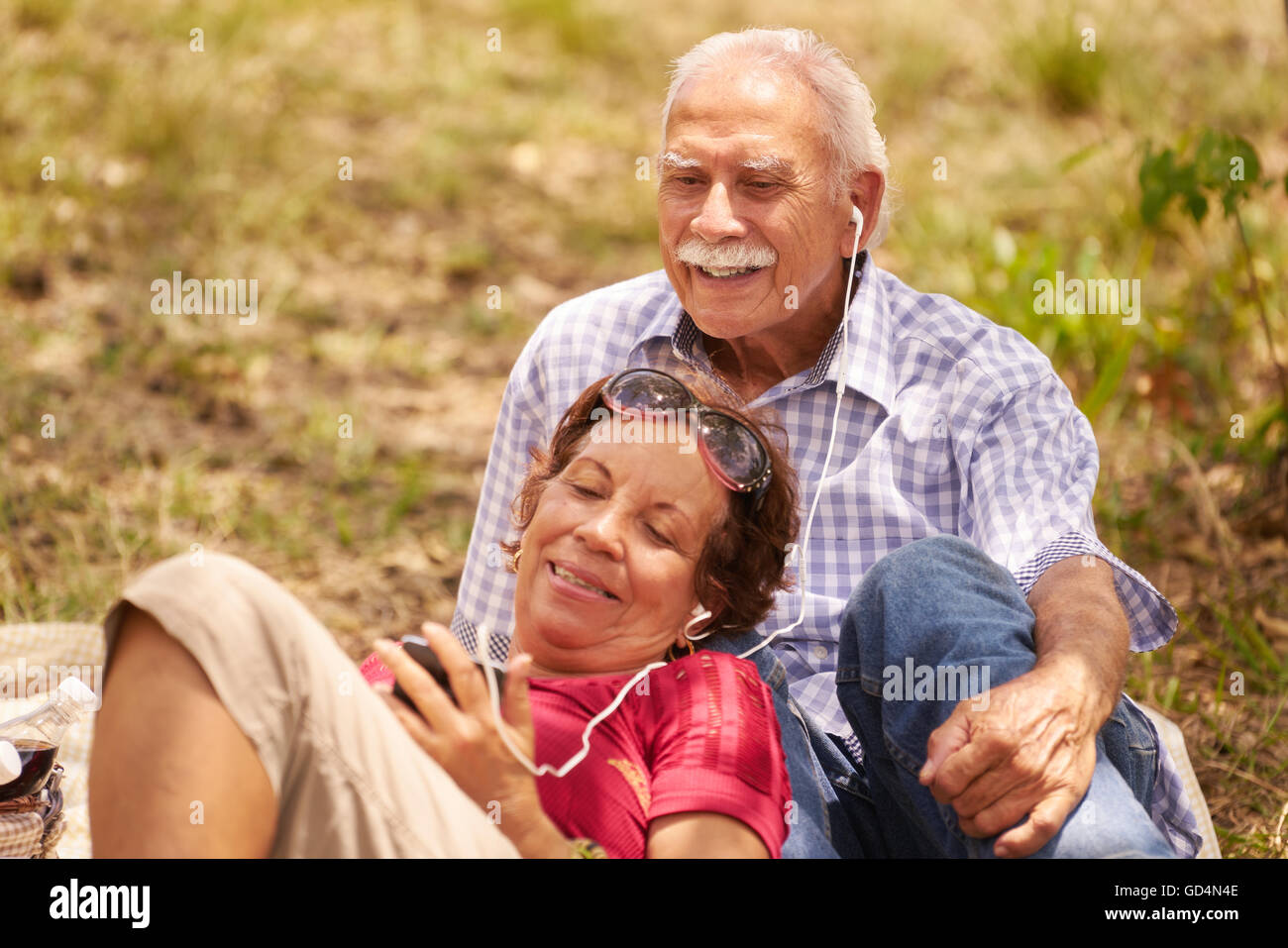 Old people, senior couple, elderly man and woman in park. Grandpa and grandma listening to song, music with mp3 player Stock Photo