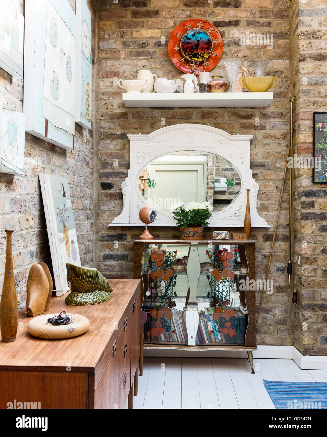 Edwardian mantel mirror in entrance hall with exposed brick walls and mirrored display cabinet Stock Photo