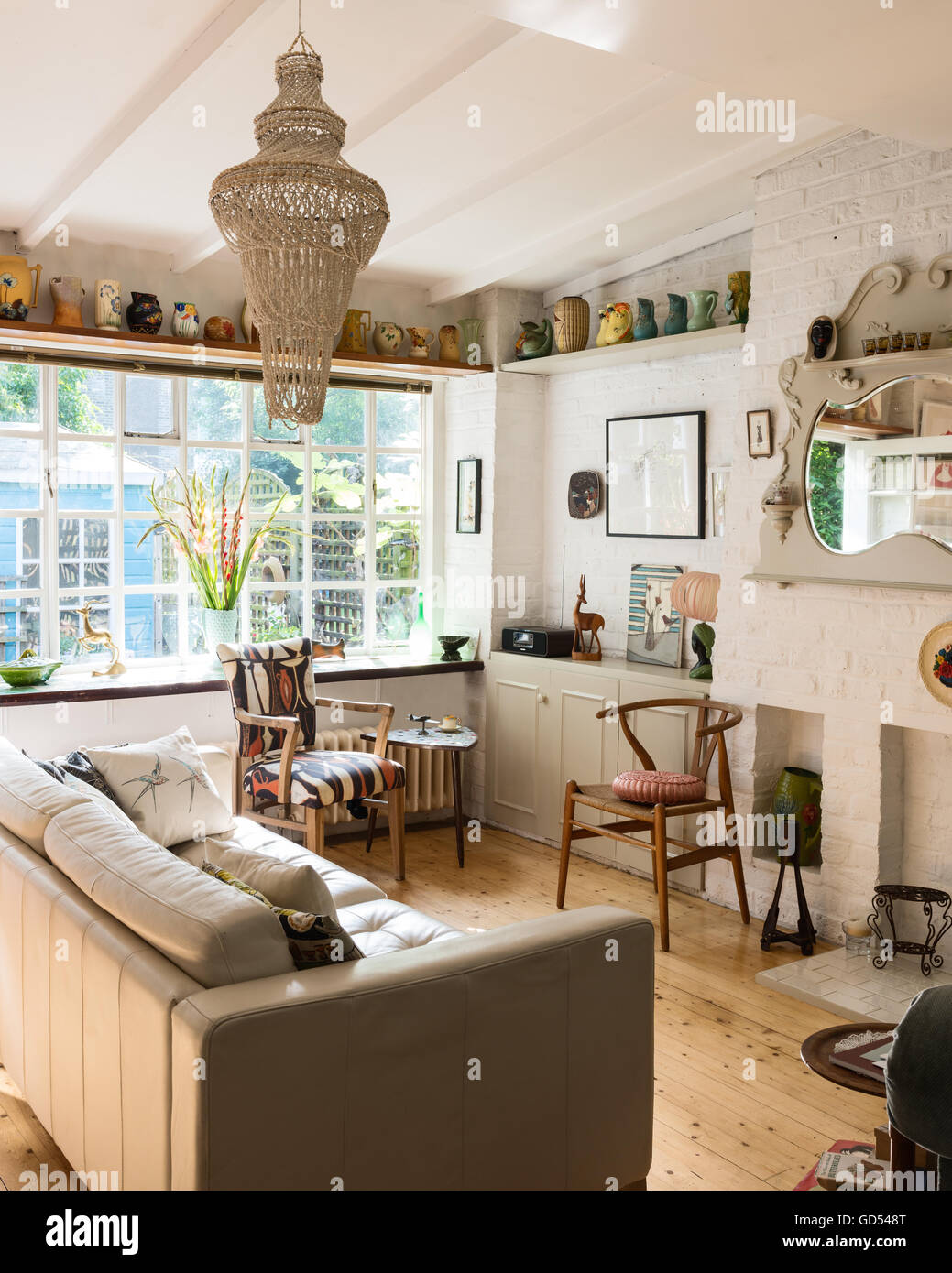 Light and airy sitting room with mantel mirror, Hans Wegner 'wishbone' chair and decorative ceramics displayed on a high-shelf Stock Photo