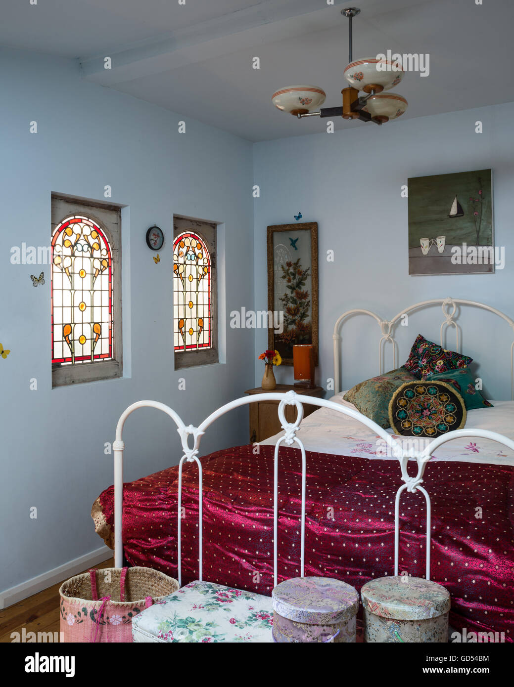 1930's stained glass windows in bedroom with wrought iron bed frame and