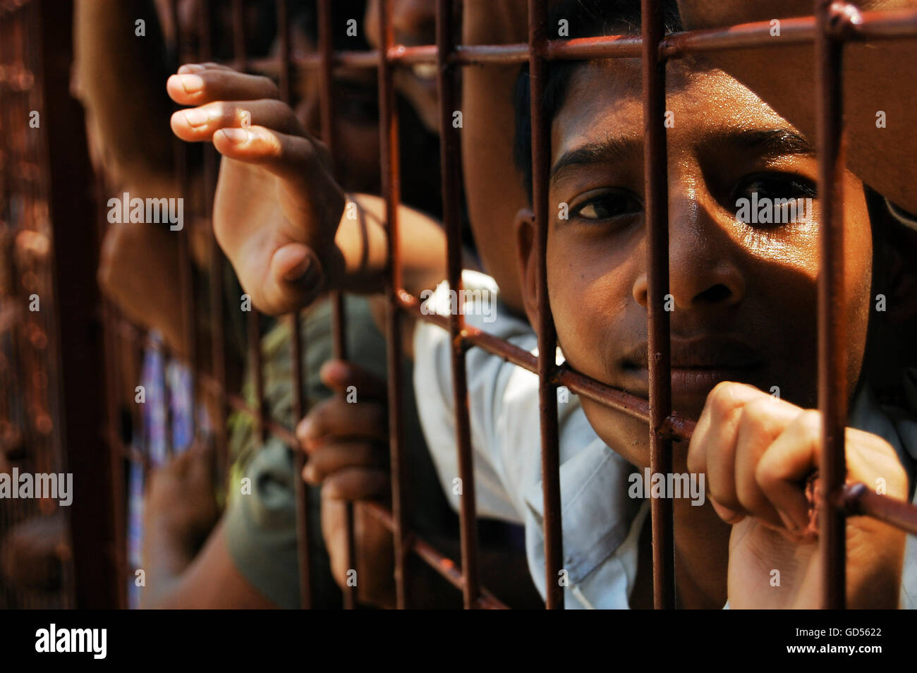 Young boy looking through bars Stock Photo - Alamy