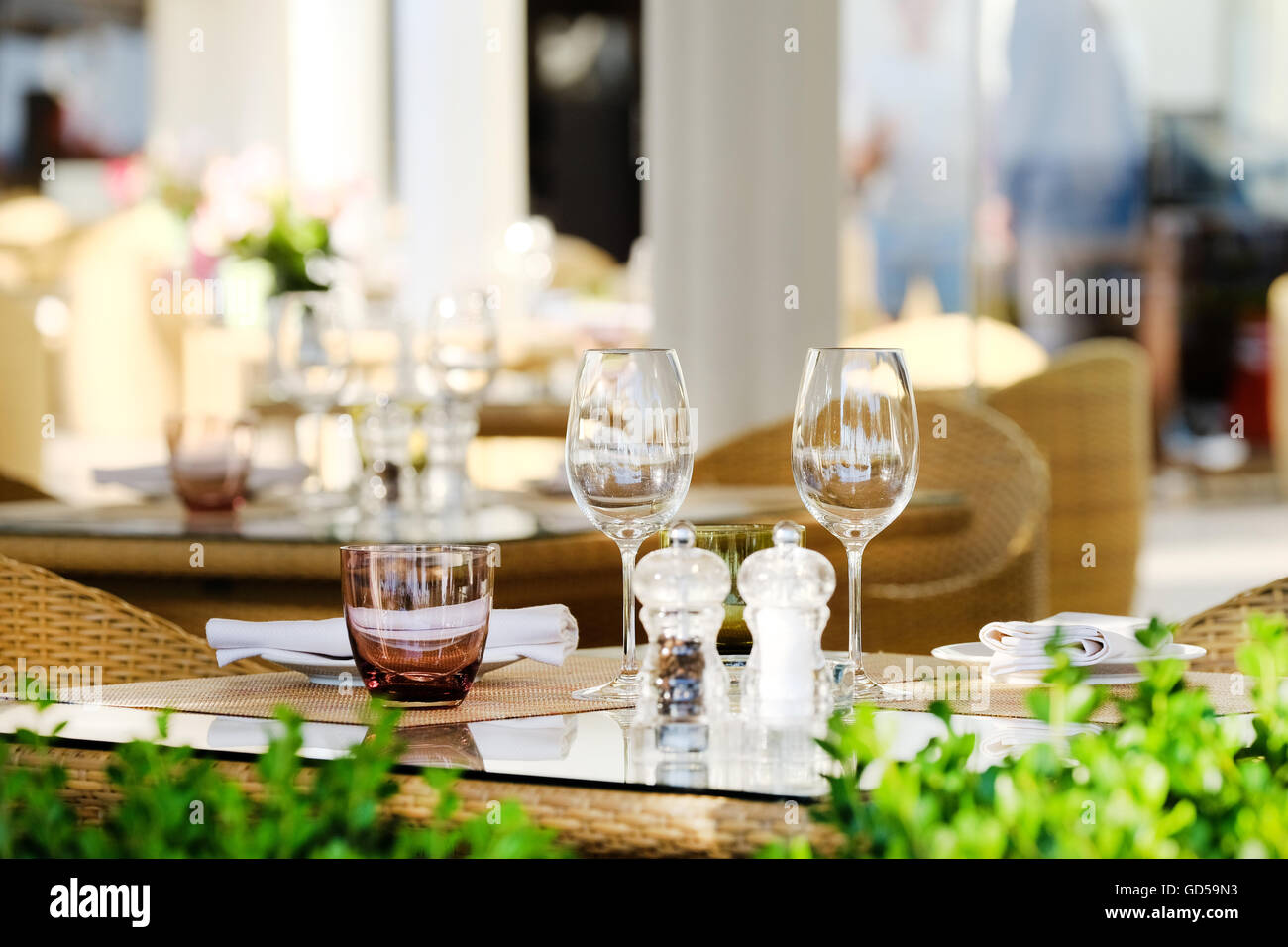 A glass topped outdoor restaurant table in Cannes, France, set up with stemmed wine glasses and waiting for that evenings customers Stock Photo