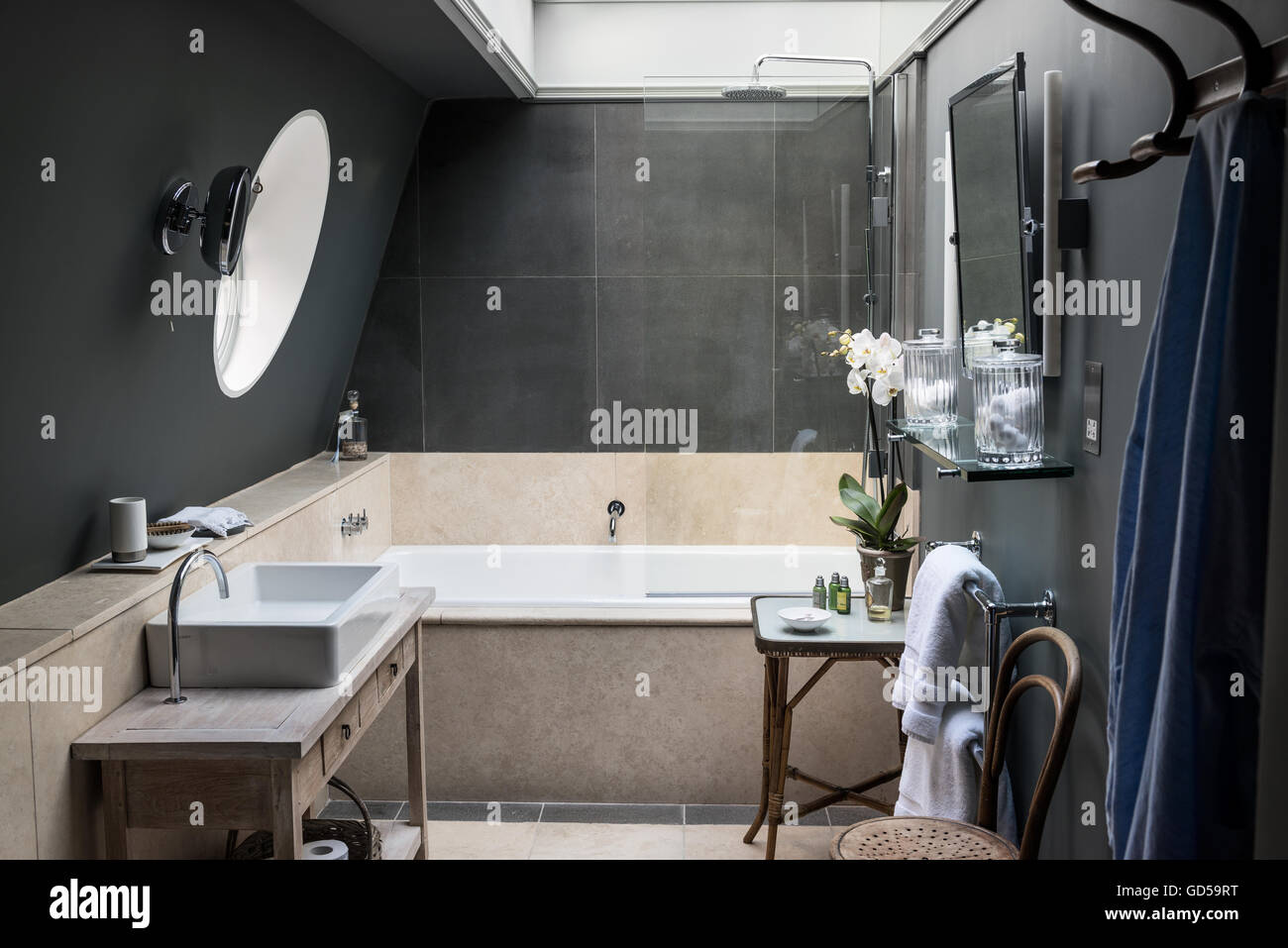 Urban Style Bathroom Painted In Downpipe By Farrow Ball With Slate Bath Surround And Travertine Wall Tiles The Mirrors Are Sr Stock Photo Alamy