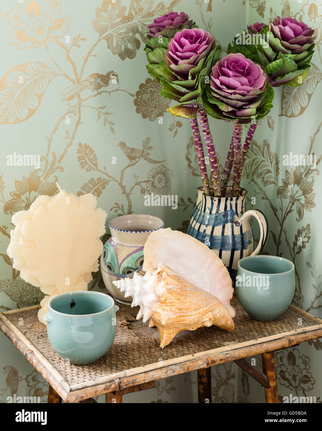 Shells, ceramics and cabbages on side table with Mark Rochester for Colefax & Fowler print wallpaper backdrop Stock Photo