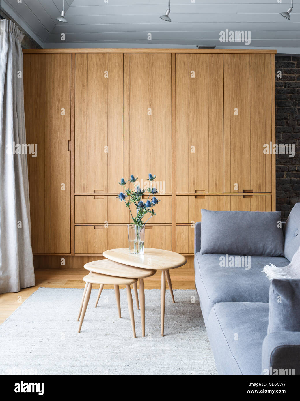 A nest of tables in front of a grey sofa by Erik Jorgensen Stock Photo