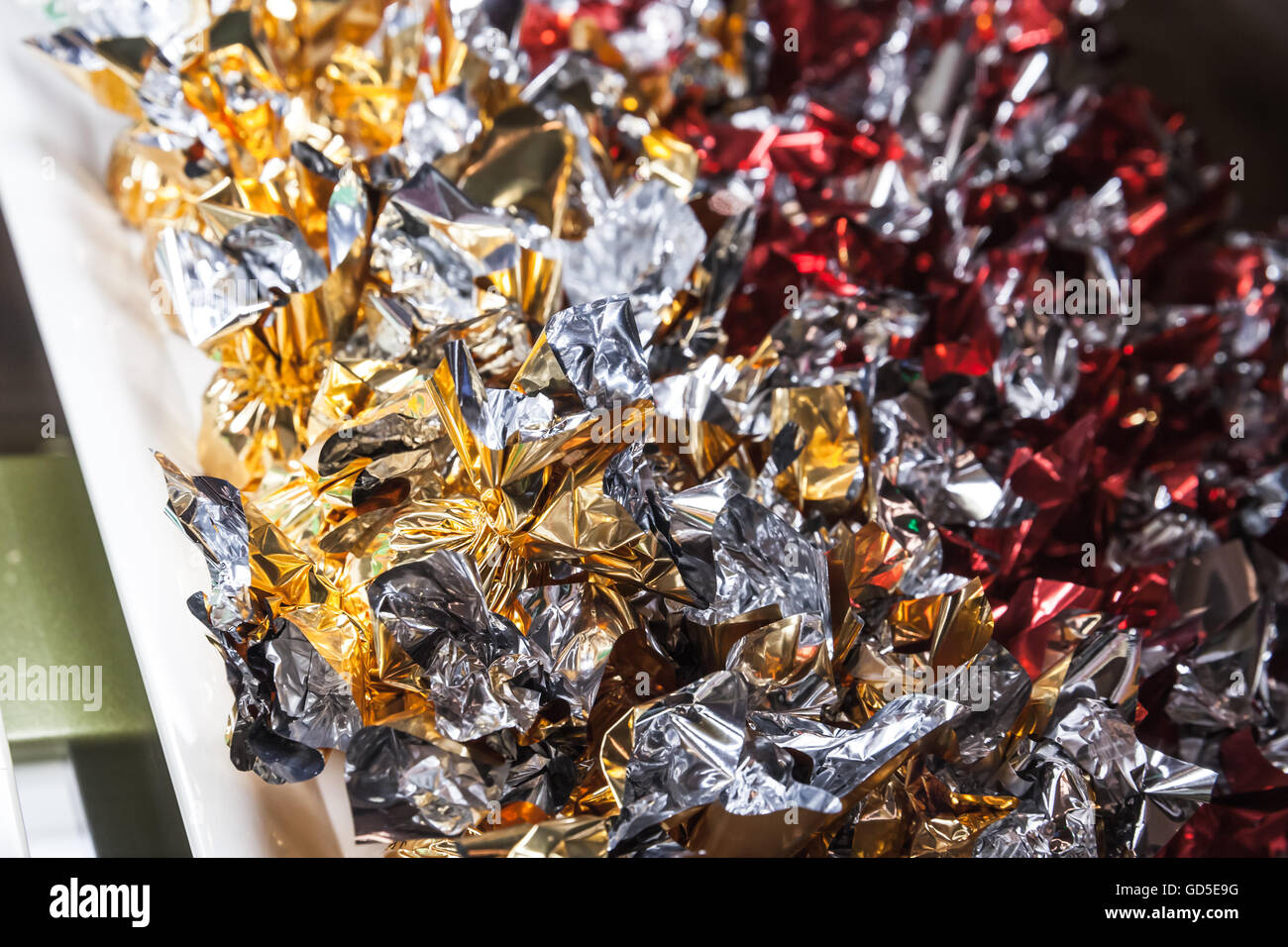 Candies in shining colorful wrappers lay on a market counter, closeup photo with selective