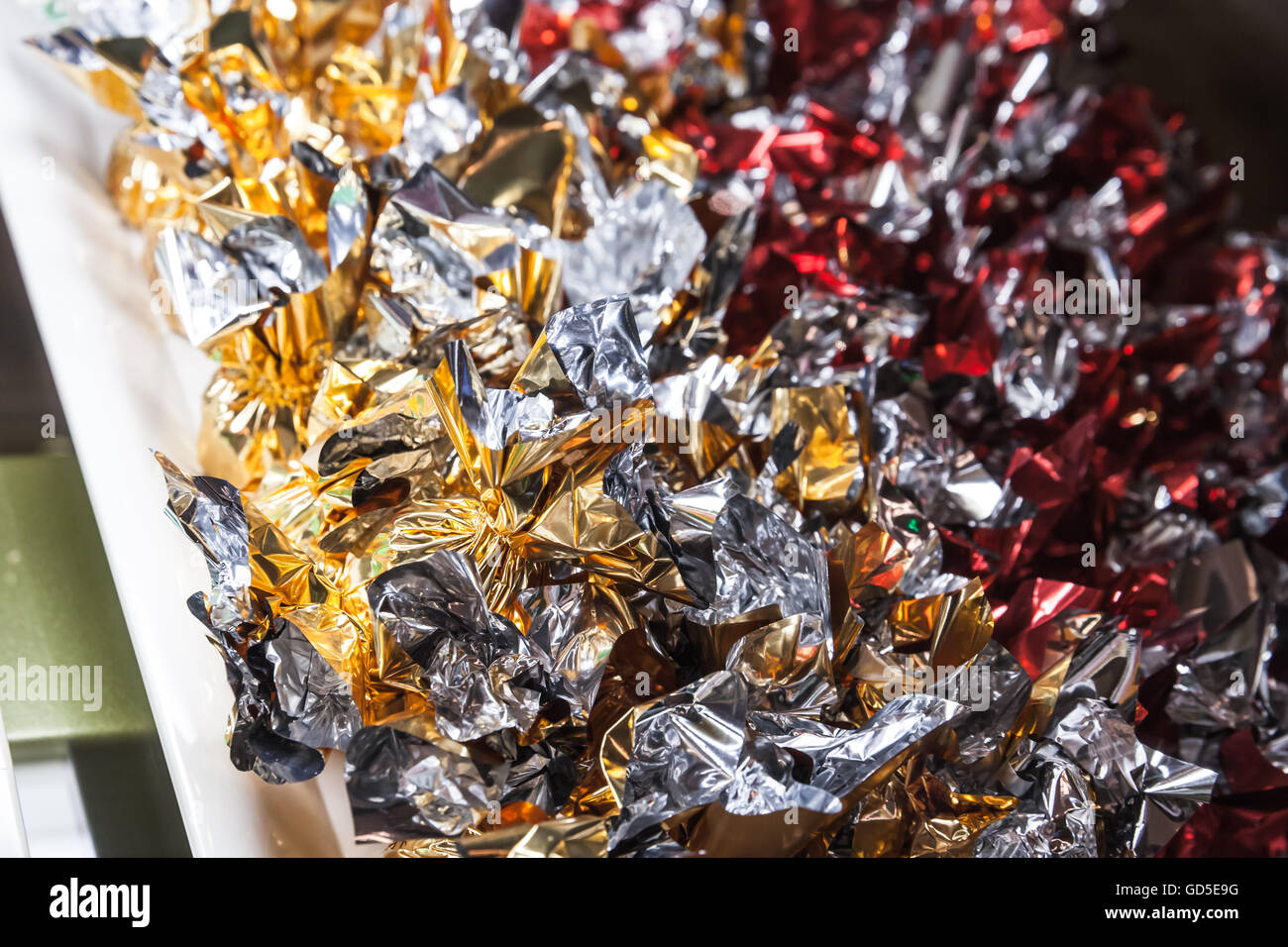 Candies in shining colorful wrappers lay on a market counter, close-up photo with selective focus Stock Photo
