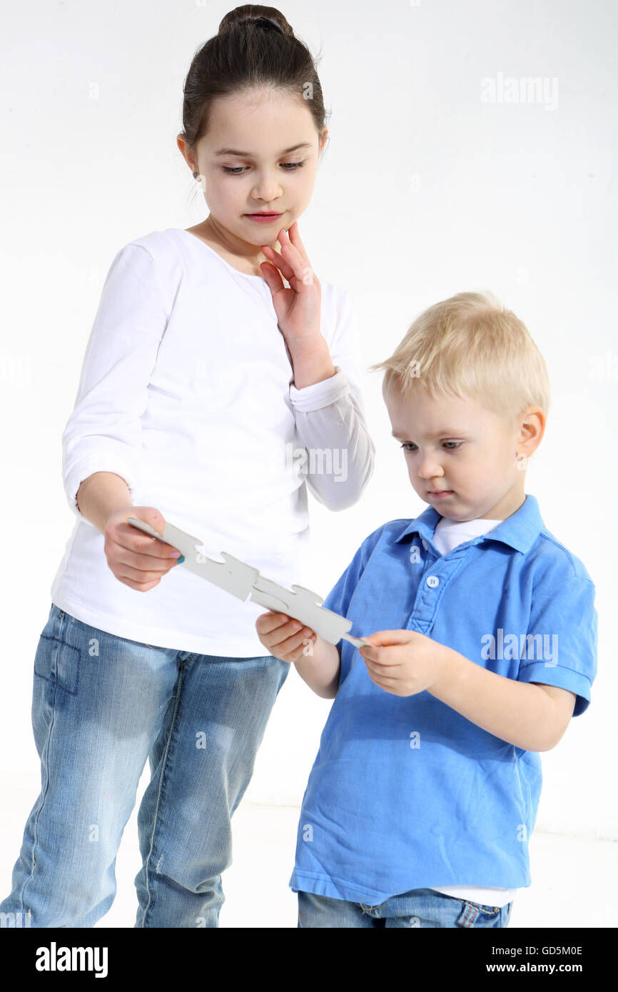 Sister and brother play with puzzle pieces isolated on white Stock