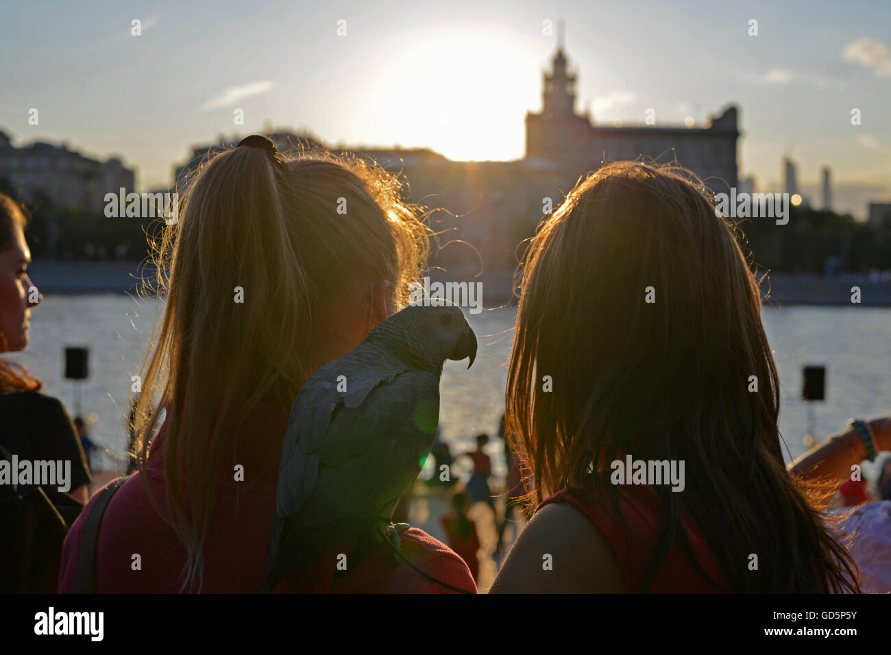 Two girls with a parrot looking at the Moscow river in Gorky Park in Moscow. Stock Photo