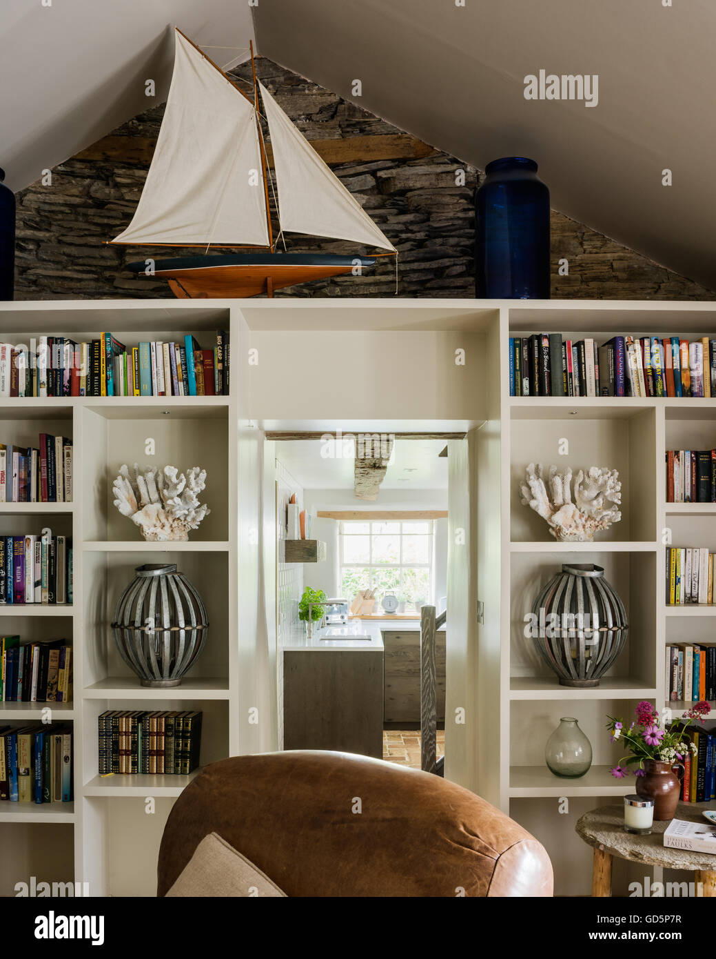 Model boat, coral and books on open shelving in sitting room Stock Photo