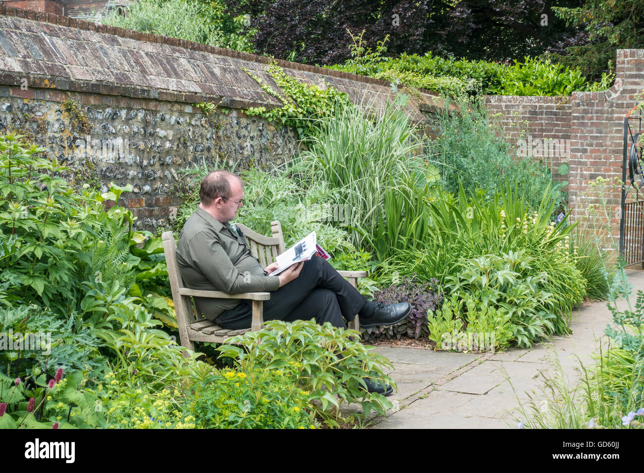 Man on Bench Reading Magazine in Quiet Park Garden Stock Photo
