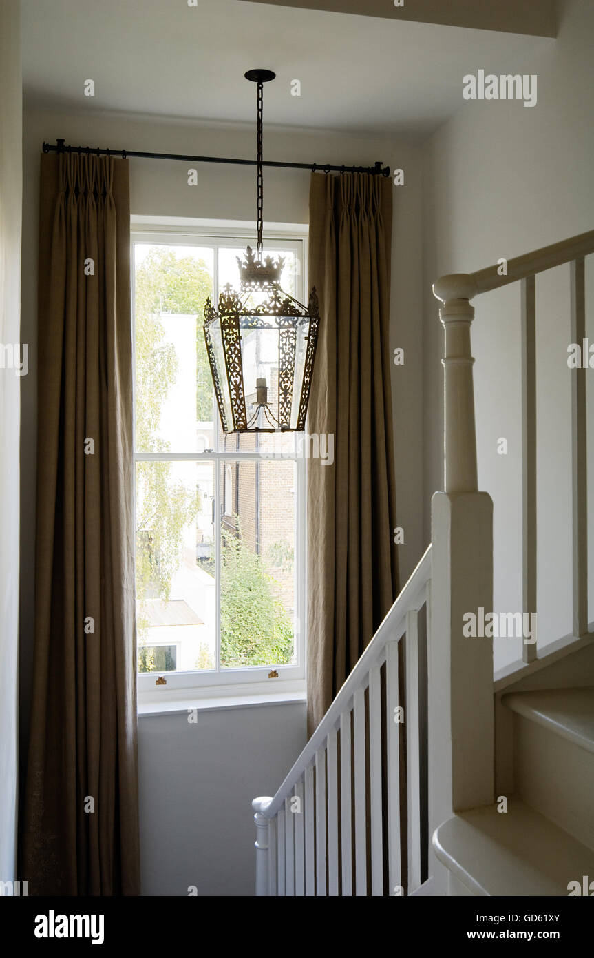 Lantern hangs above staircase with fulllength curtains in Portland Road, London, UK Stock Photo