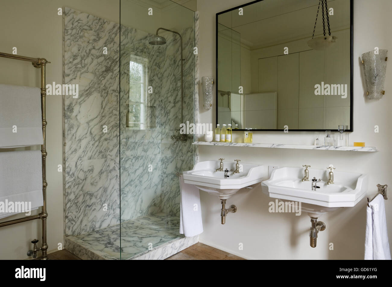 Marble shower unit and shelf with toiletries above washbasins in Portland Road, London, UK Stock Photo