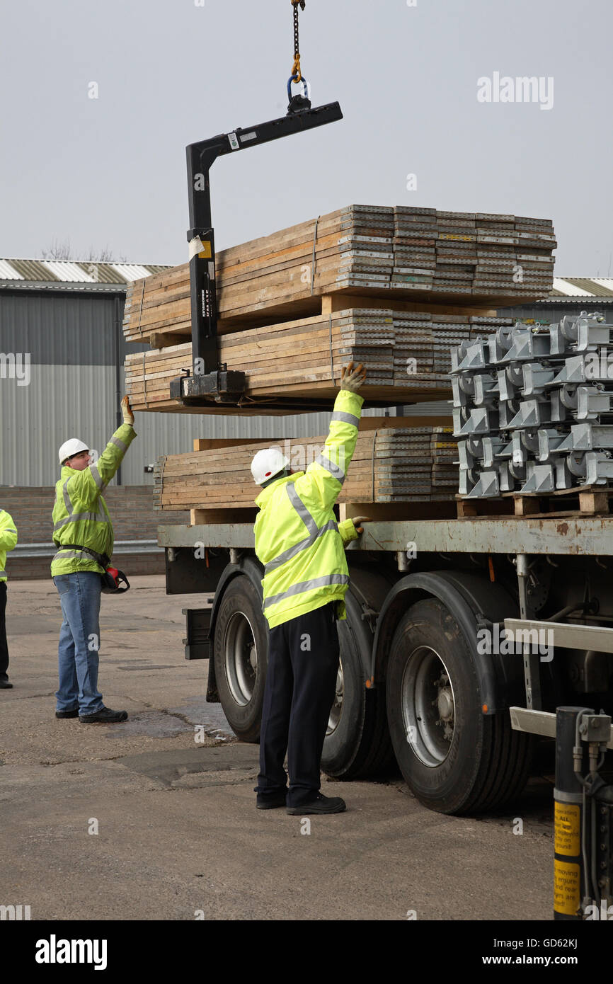 A lorry uses a cab-mounted Hiab crane to unload steel building products in a demonstration of safe loading procedures Stock Photo