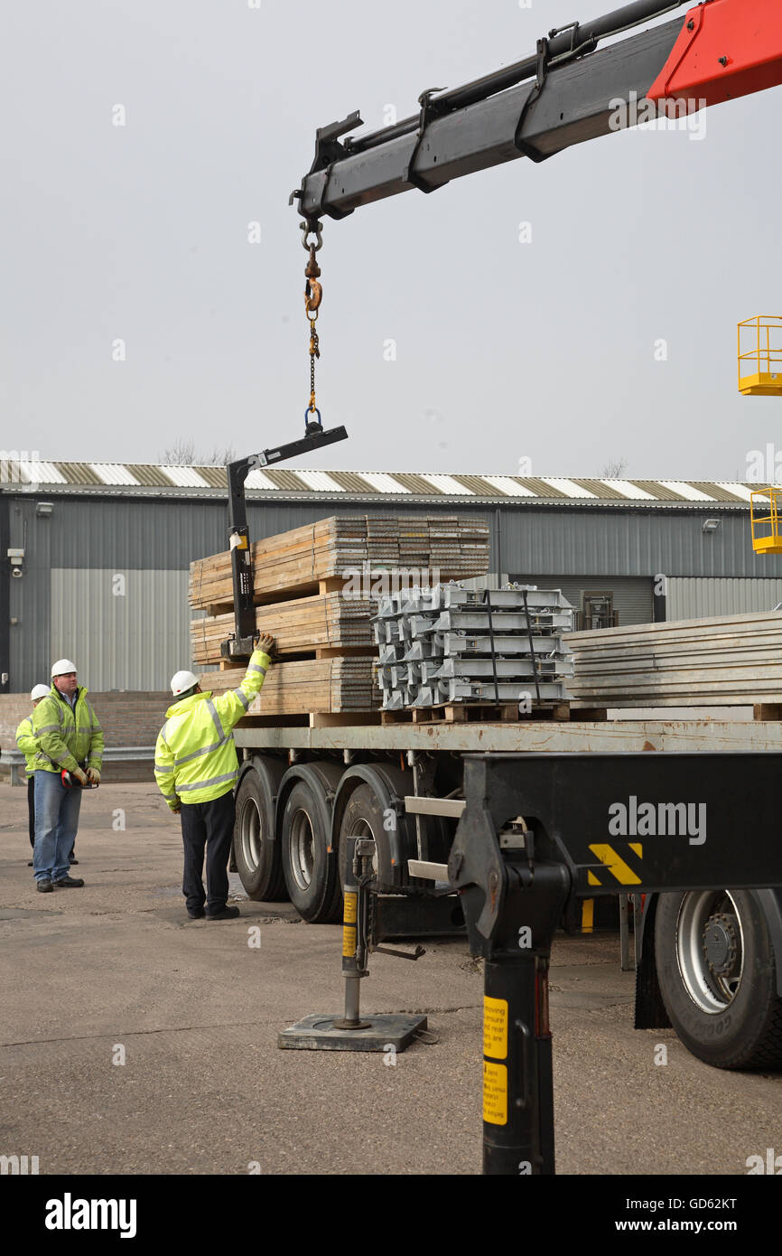 A lorry uses a cab-mounted Hiab crane to unload steel building products in a demonstration of safe loading procedures Stock Photo