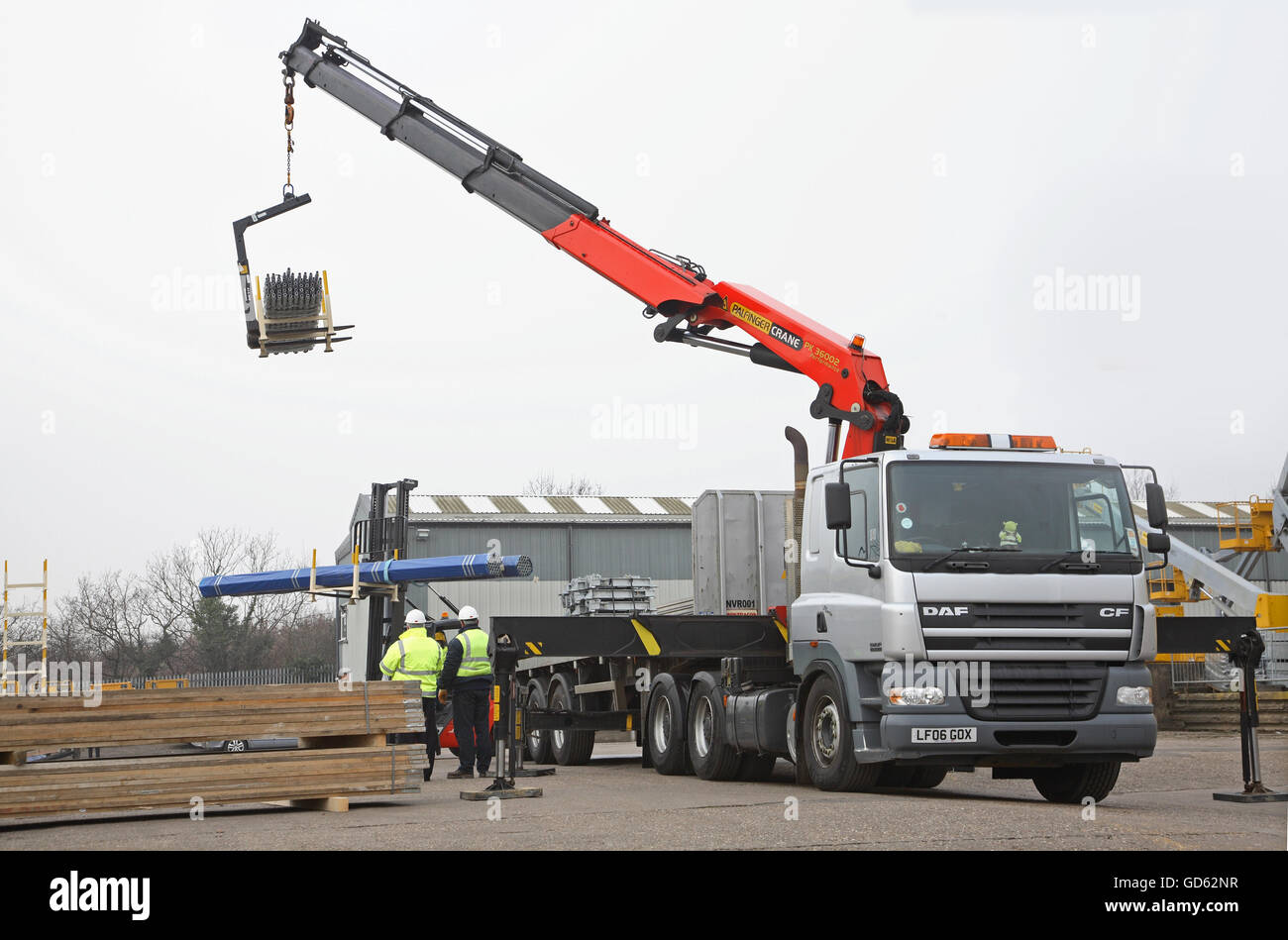 A cab-mounted Hiab crane and a fork lift truck are used to unload steel building products in a demonstration of safe loading Stock Photo