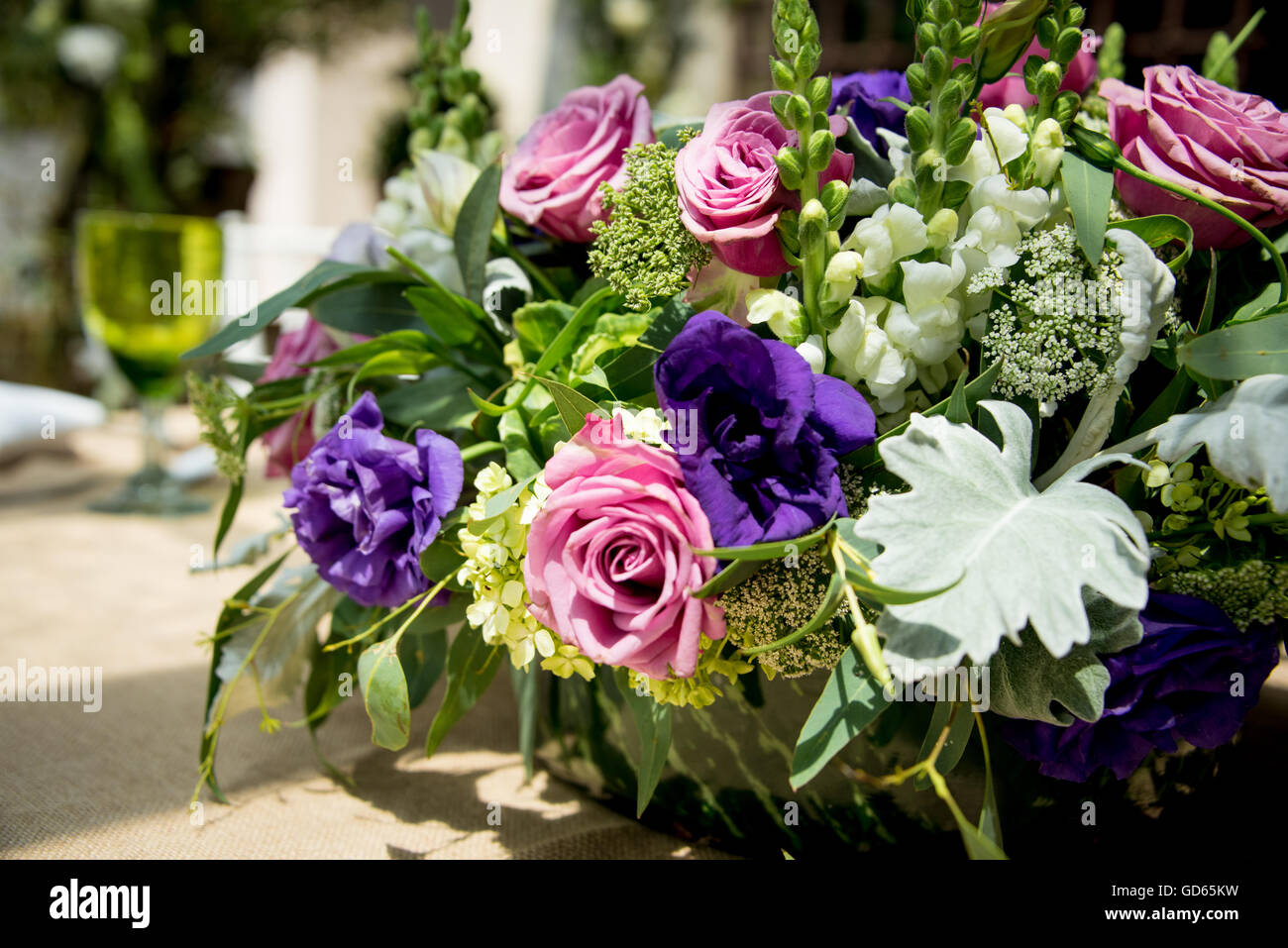 Floral table centerpiece at a wedding reception with an arrangement of pink and purple roses amongst assorted white flowers and Stock Photo