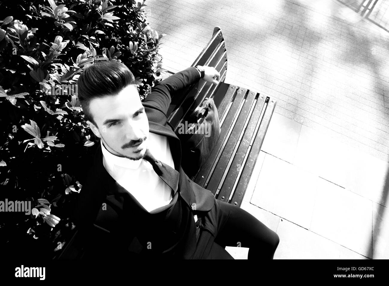 Portrait of a young businessman sitting on a bench Stock Photo - Alamy