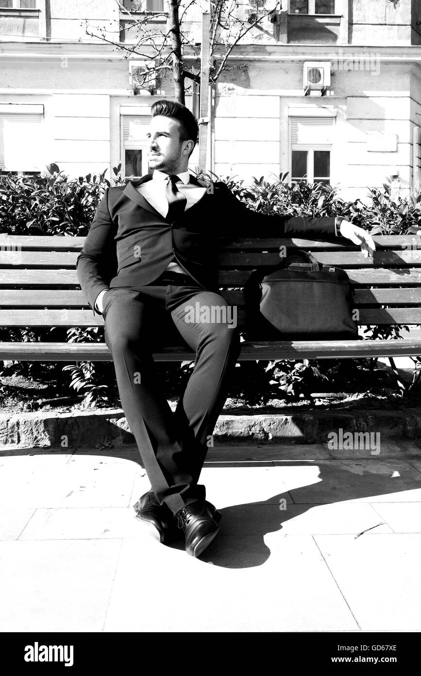 Portrait of a young businessman sitting on a bench Stock Photo - Alamy