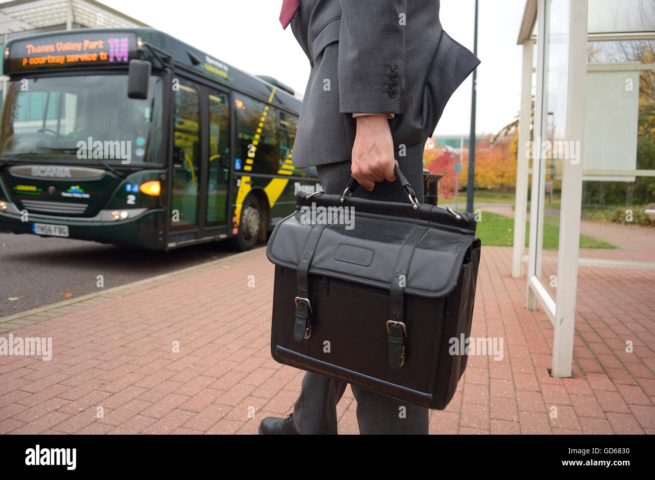 unrecognizable businessman waiting at a bus stop to catch the bus shuttle to the railway station, England. UK Stock Photo