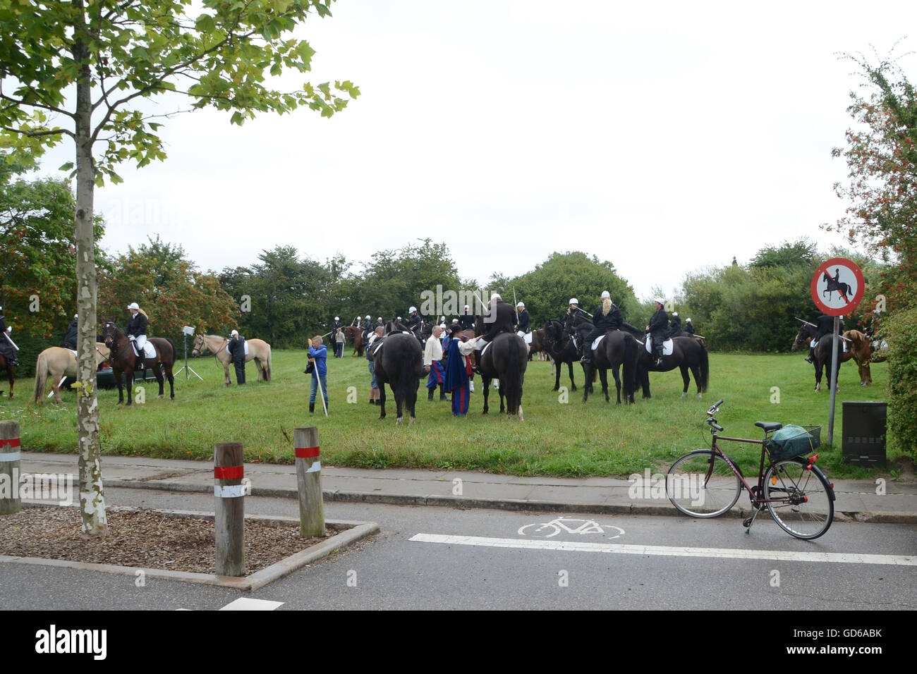 Many riders with their horses meet on a lawn, the funny thing is that there is a sign that says no riding. Stock Photo