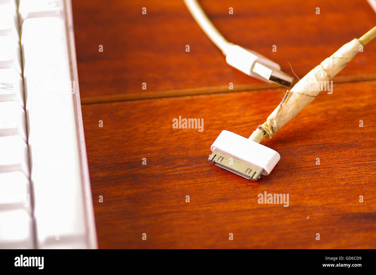 Broken usb mobile charger cable lying on wooden surface, masking tape used  to fix wire Stock Photo - Alamy