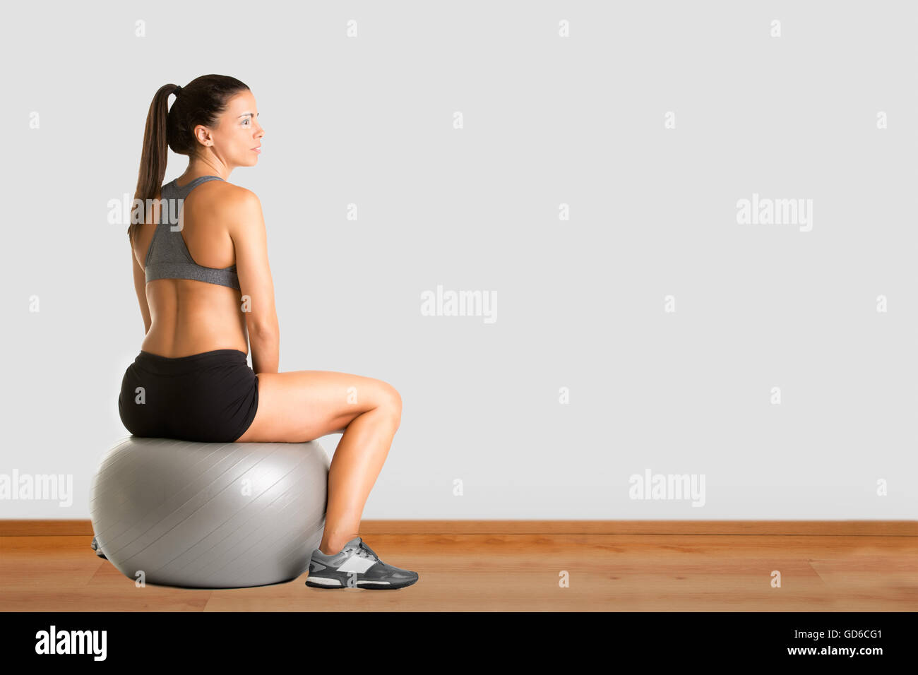 Fit woman sitting on a yoga ball, in a gym Stock Photo