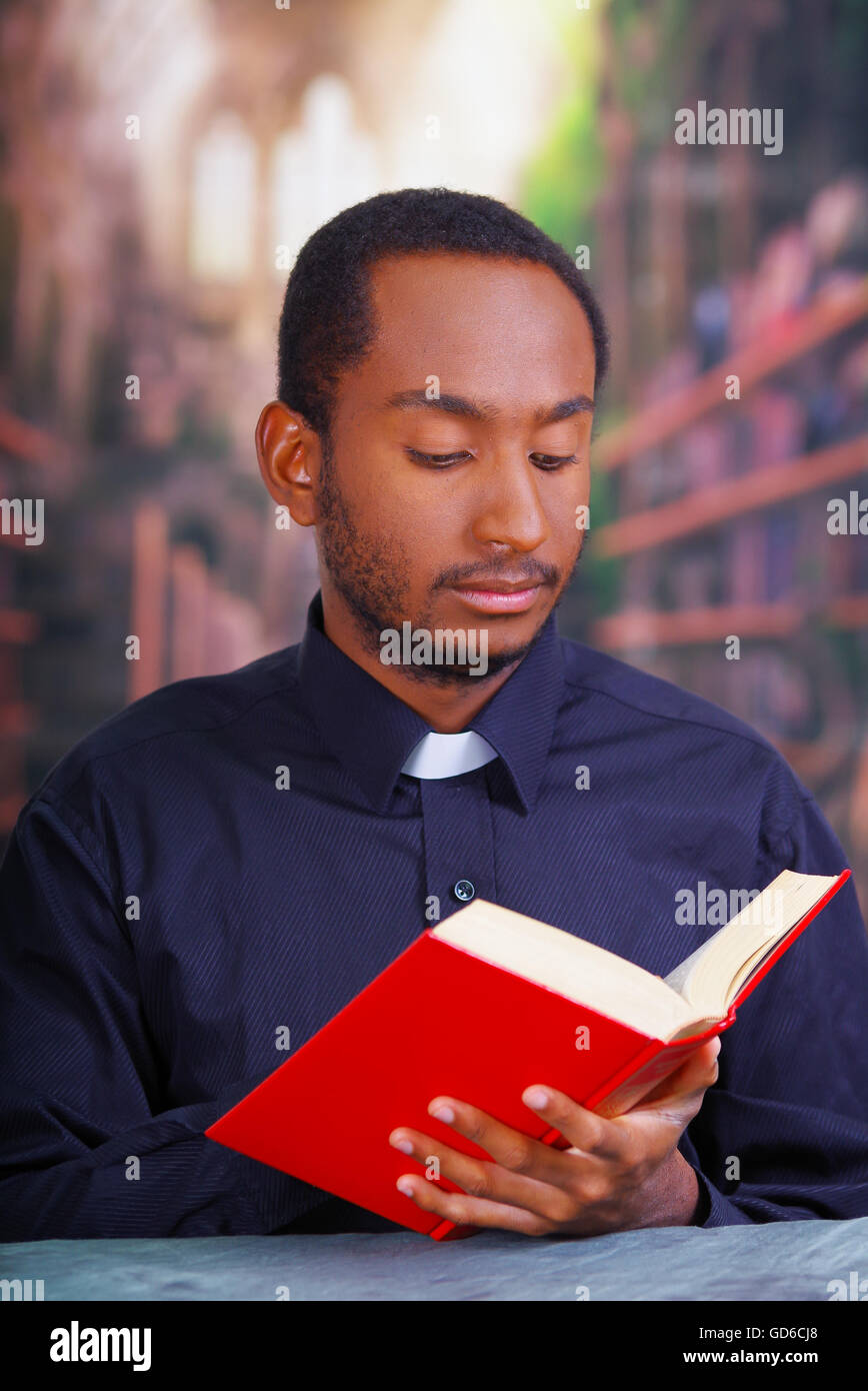Catholic priest wearing traditional clerical collar shirt sitting and holding bible while