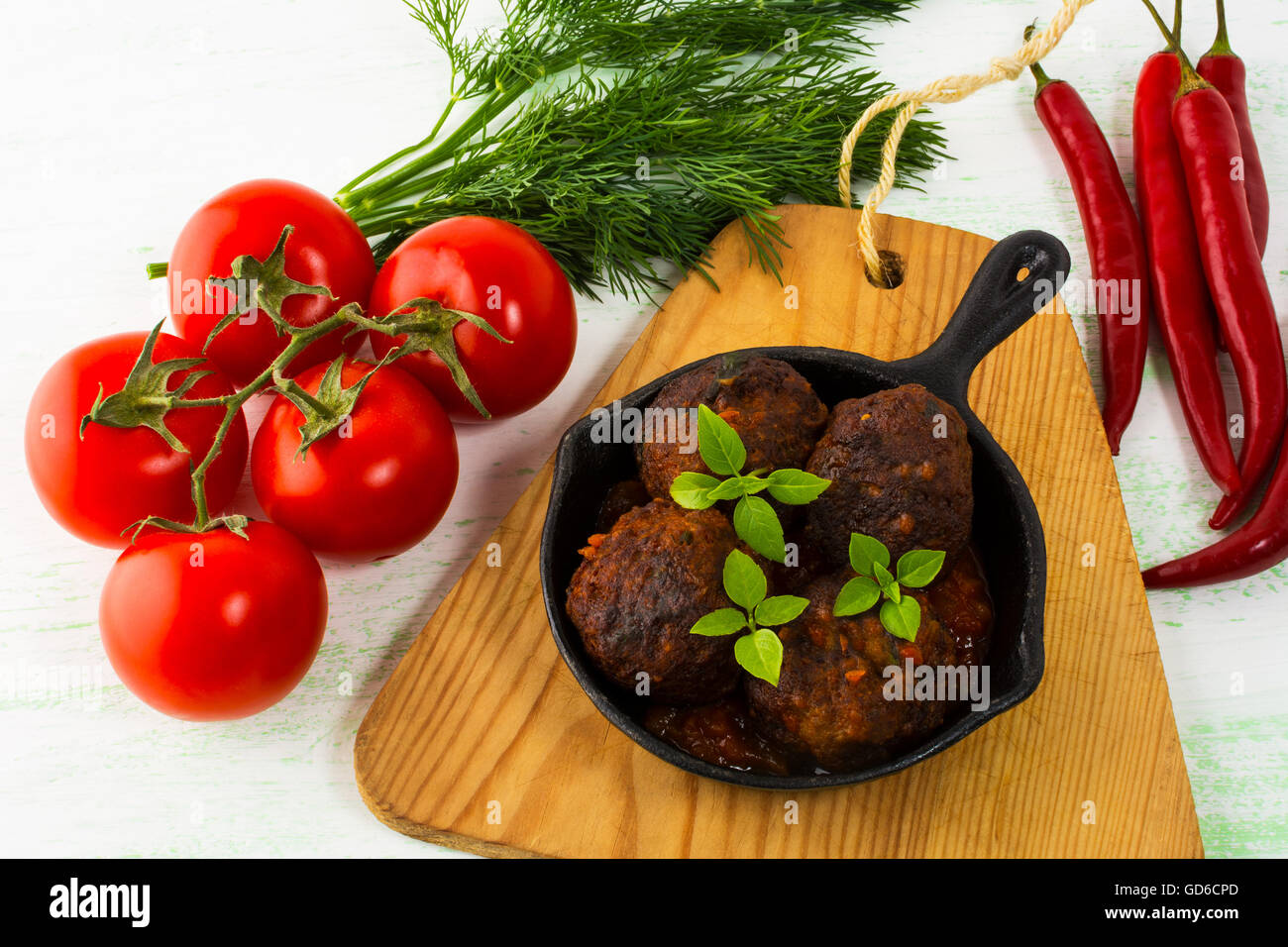 Grilled meatballs with chili pepper and tomato served in cast iron