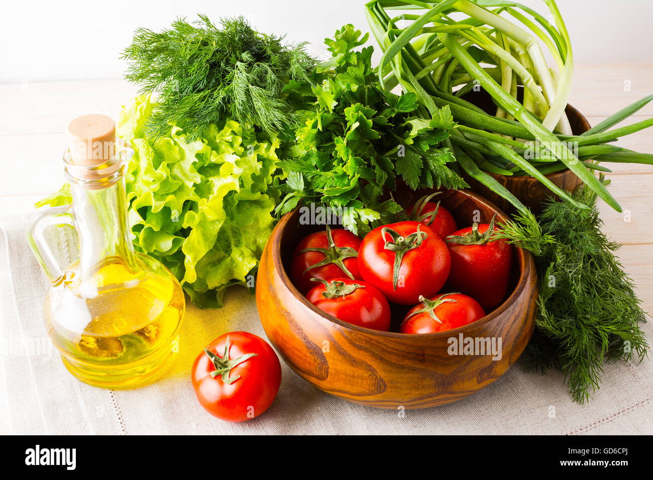 Olive oil, garlic and tomato in wooden bowl.. Healthy eating concept with fresh vegetables. Vegetarian  vegan food. Stock Photo