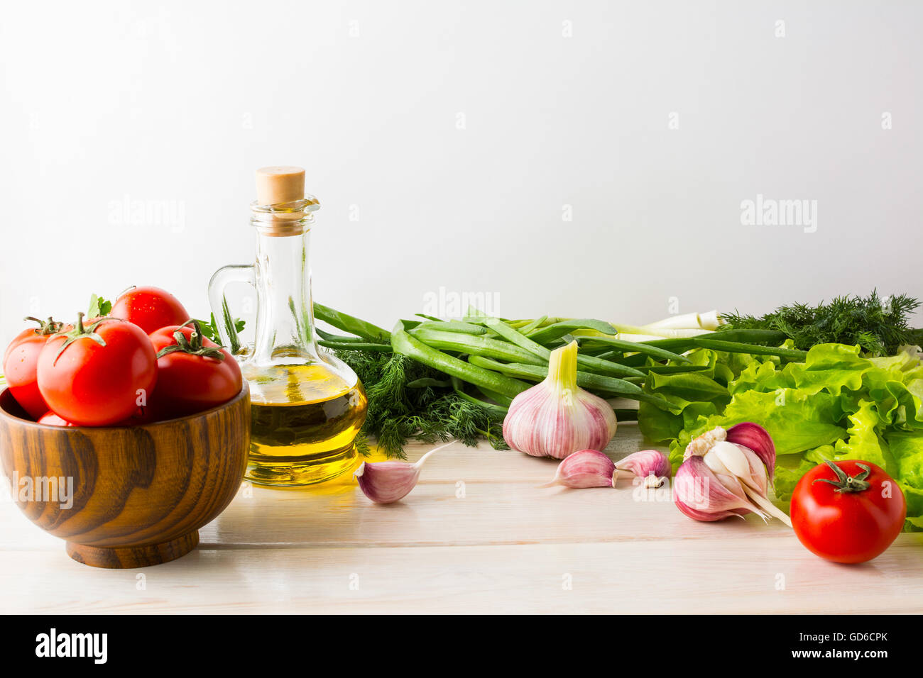 Olive oil, garlic and tomato on the white wooden background. Vegetarian  vegan food background. Healthy eating concept with fres Stock Photo